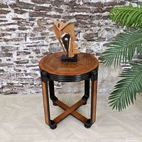 Full frontal view of round table with sculpture and plant on top