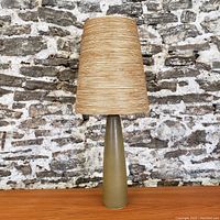 Full view of lamp on wooden surface against a stone background