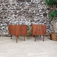 Two matching walnut nightstands side by side against brick wall