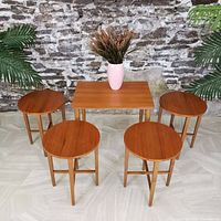 Front view of rectangular table with four round tables nested underneath, staged with vase