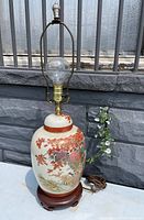 Front view of the antique ginger jar table lamp showing floral and bird motifs on the ceramic base and wooden stand with lamp hardware attached.