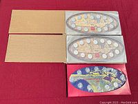 Three Canadian Millennium quarter sets in oval plastic holders, two from 1999 in beige packaging and one from 2000 in blue packaging.