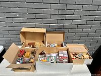 Overview of all boxes containing vintage dollhouse furniture and various accessories spread out in natural light.