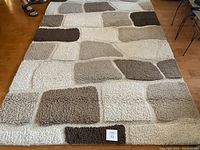 Full view of area rug showing geometric pattern and neutral colors, with a label marked 73 in bottom center.