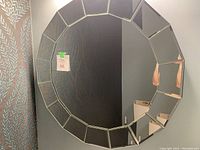 Round wall mirror with segmented glass border displaying geometric design in a powder room setting