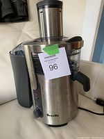 Front-side view of Breville juicer showing metal body, control knob, and juice spout