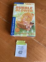 Photo of sealed box of Thames & Kosmos Bubble Blower experiment kit with auction lot tag placed on it.