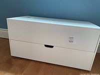 Closed view of the white craft storage cabinet showing its smooth front with two drawers and cutout handles.