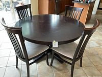 Full set showing round dining table and four chairs around it on tiled floor.