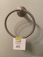 Front view of a circular brushed nickel hand towel ring mounted on a wall showing style and condition.