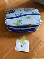 Closed dinosaur pattern kids lunch box with blue zipper and handle.