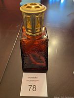 Clear front angle of the brown textured glass Lampe Berger fragrance lamp with gold-tone metal top showing details and wick inside.