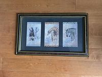 Full view of the framed safari picture on the floor showing three animal panels and the decorative frame.