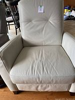 Front view of white faux leather recliner showing seat and back cushions with some creasing.