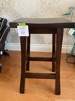 Front view of wooden black brown counter stool showing square top and four legs with connecting support rails.