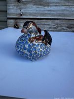 Side and front view of the Andrea By Sadek ceramic duck figurine showing bright blue, brown, and gold detailing on ceramic material.