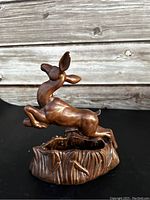 Side angle of the ceramic painted deer figurine mounted on a textured base, showing detailed sculpting and paint.