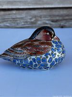 Front-side view of the hand painted porcelain duck showing detailed feather pattern and blue floral design on the belly.