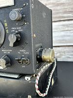 Side view of LM-21 frequency meter showing control knobs and power connector with braided cable.