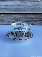 Tea cup and saucer displayed together with detailed portraits and royal decorations.