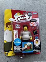 Front view of the Brad Goodman action figure in original sealed blister packaging with accessories and Simpsons branding.