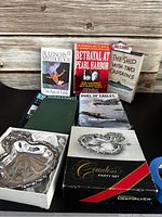 Books and silver party set displayed on black surface with wooden background.