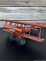 Front angled view showing the full biplane with rusty reddish paint, propellers, and landing gear wheels.