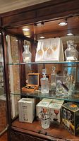 Glass shelves with champagne glasses in protective case, decanters, and boxed glassware sets.