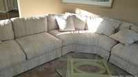Full view of the off white curved sectional sofa arranged in a U shape in a living room with sunlight cast on it.