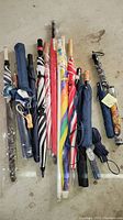 Top view of 11 assorted umbrellas including wooden handled, compact, and patterned styles