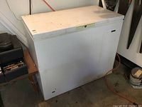 General chest freezer closed, showing white exterior with slight scuffs