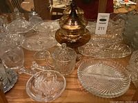 Collection of assorted glass and crystal serveware including covered jars, glass bowls and platters with intricate patterns in clear and amber glass.