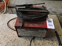 Top view of mini-welder unit with cables and attachments laid on a carpeted floor