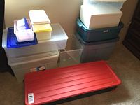 Photo of assorted storage totes stacked together, showing the variety of sizes and colors including the large rectangular red-lid tote