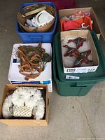 Multiple boxes and bins containing various items including macrame lampshades, floral decor, and wooden duck wall hangings, plus a box with wool/knit material likely owl wall hanging parts or related textile.