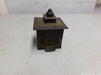 Front angled view of the antique Excelsior metal bank showing shape and top opening.