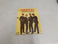 Front cover of 1964 Beatles official coloring book by Saalfield, featuring the Beatles group photo on yellow background.