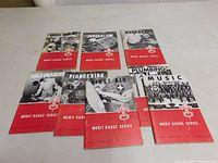 Arranged view of all eight vintage Boy Scout Merit Badge booklets on flat surface, showing front cover designs and titles, including years and themes.