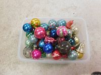 Top-down view of a container filled with assorted vintage Christmas bulbs in multiple colors and finishes.