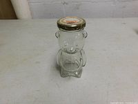 Front view of a clear glass jar shaped like a bear