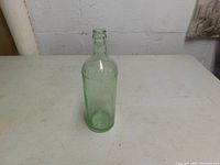 Front view of one green tint Moxie bottle on a white surface