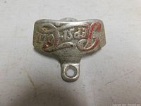 Front view of metal wall-mounted bottle opener with visible raised Pepsi logo and chipped red paint.