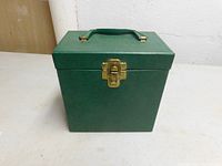 Closed green vintage record box with gold latch and handle, showcasing overall condition and design.