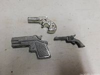 Photo showing all three toy cap guns together on a flat surface, highlighting size and design differences.