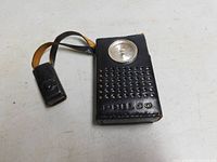 Front view of small black leather case containing Philco transistor radio, showing circular tuning dial and ventilation holes with PHILCO branding