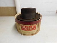 The vintage brown men's hat resting on its original round beige box with red Outlet Company Providence label.