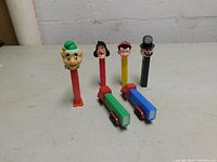 Front view of six PEZ dispensers including elf, Captain Hook, Pinocchio, snowman, and two truck dispensers