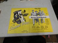Photo of a vintage sheet music booklet with a yellow cover featuring 'The Student Prince' and 'Guys and Dolls' musical titles and character illustrations.