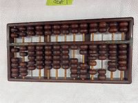 Top view showing the wooden abacus with multiple vertical rods and wooden beads used for calculations.