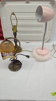 Three lamps together showing the small burnt orange lamp with tassels, medium antique bronze lamp stand, and tall light pink lamp with feathers.